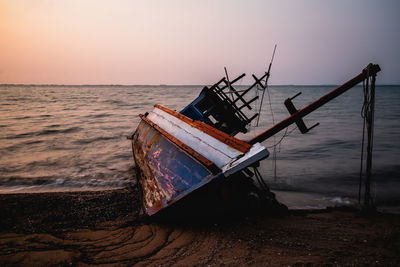 Fishing boat on sea against sky during sunset