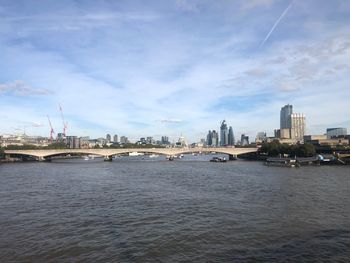 View of bridge over river by buildings against sky