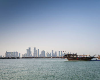 Sea by buildings against clear sky