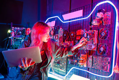 Rear view of woman using digital tablet at night