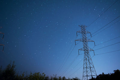 Low angle view of electricity pylon against sky at night