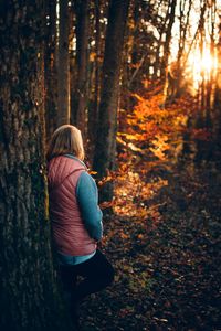 Rear view of woman standing in forest during sunset