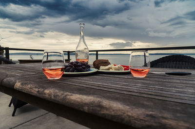 Backyard rustic wooden table with wine by cheese with bread and grapes under storm clouds