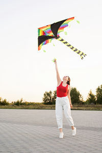 Woman holding umbrella standing against the sky