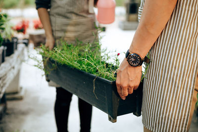 Midsection of woman holding umbrella standing by plant