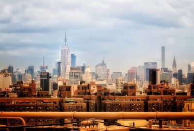 Buildings in city against cloudy sky