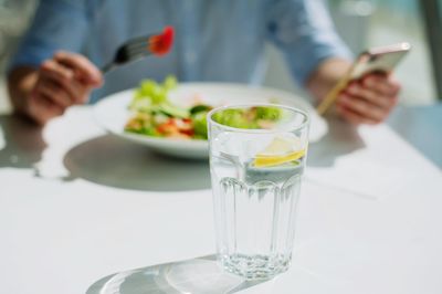 Midsection of person holding drink in glass on table