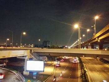 Illuminated city street against sky at night