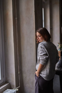 Woman looking through window at home