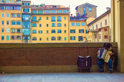 Man playing accordion against retaining wall