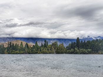 Scenic view of lake by trees against sky