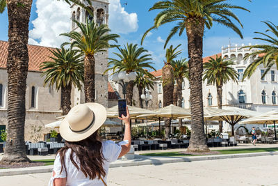 Female tourist using mobile phone to take photos in beautiful town of trogir in croatia
