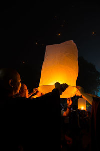 People holding lit paper lantern during night