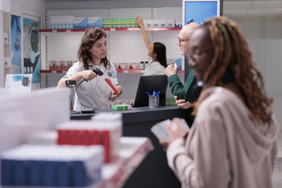 Portrait of smiling female friends using smart phone while sitting in laboratory