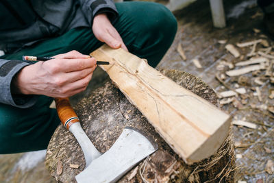 Midsection of carpenter drawing on wood