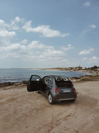 Vintage car on beach against sky