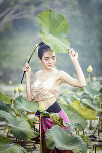 Portrait of young woman holding leaves outdoors