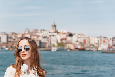 Portrait of beautiful woman in city against sky