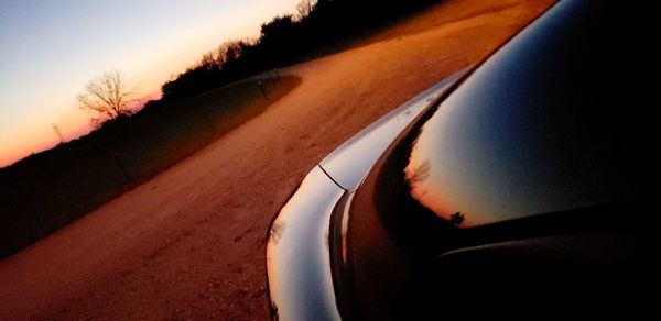 Close-up of car on road against sky during sunset