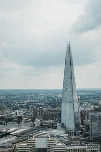 Aerial view of buildings in city against cloudy sky