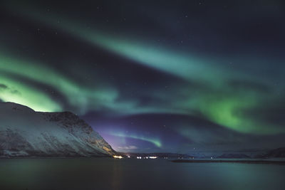 Scenic view of sea and mountains against sky at night