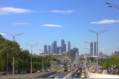 Traffic on city street by buildings against sky