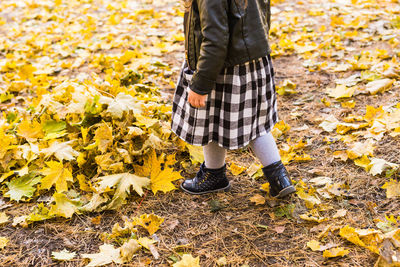 Low section of man standing on autumn leaves