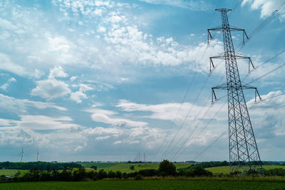 Low angle view of electricity pylon on field against sky