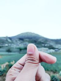 Close-up of human hand against mountain