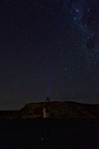 Man standing on field against sky at night