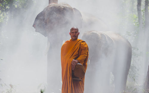 Man standing on cross against foggy weather