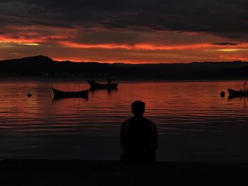 Silhouette people in sea against sky during sunset