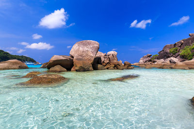 Rock formations in sea against blue sky