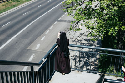 High angle view of woman photographing road while standing on steps