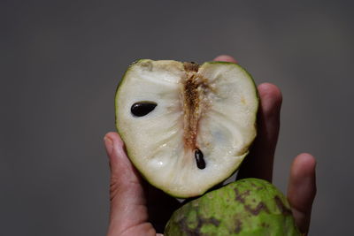 Close-up of hand holding apple against black background