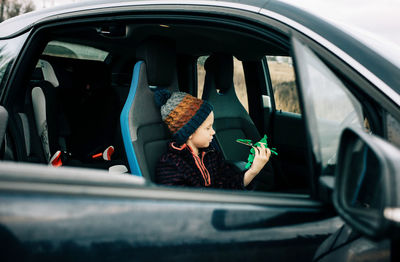 Young boy sat in an electric car playing with toys