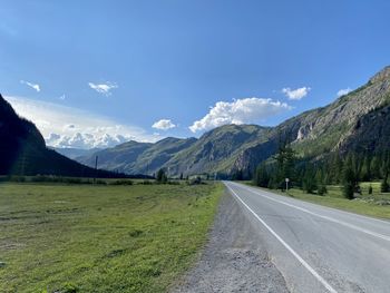 Road leading towards mountains against sky