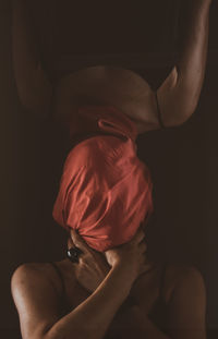 Midsection of shirtless man sitting against black background