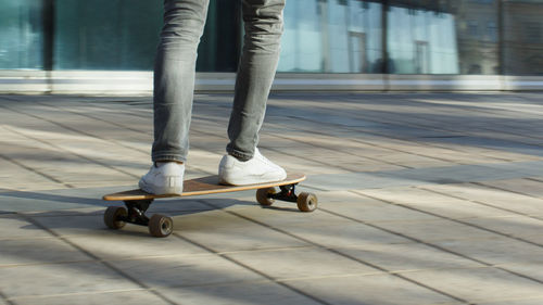 Man in white sneakers down street with skateboard. leisure, healthy, active lifestyle, extreme sport