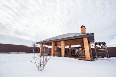 House on snow covered field against sky