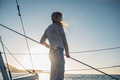 Rear view of woman fishing in sea against clear sky