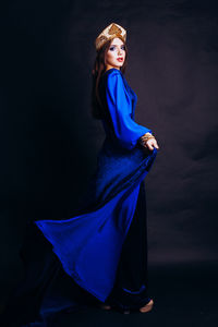 Portrait of beautiful woman in traditional clothing standing against black background