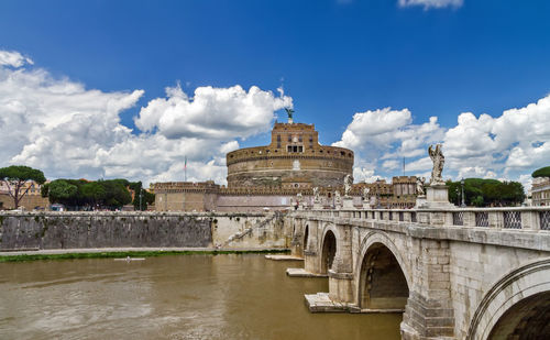 Arch bridge over river against cloudy sky