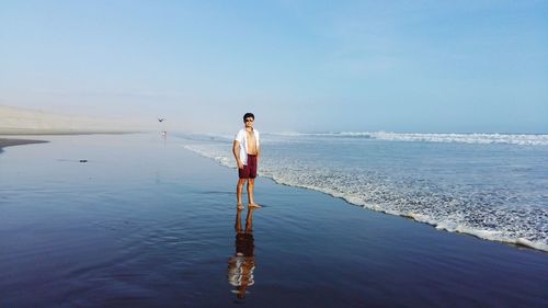 Rear view of shirtless man walking in sea
