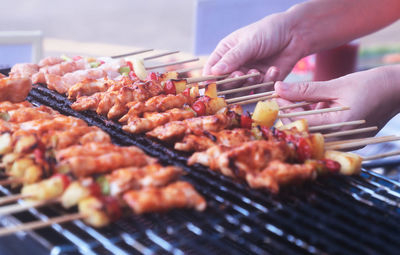 Close-up of person preparing food on barbecue grill