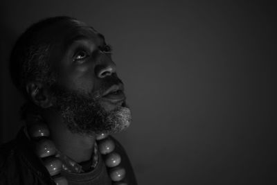 Portrait of young man looking away against black background