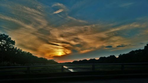 Silhouette landscape against dramatic sky during sunset