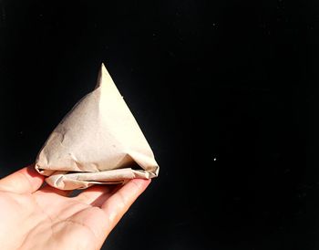 Close-up of hand holding ice cream against black background