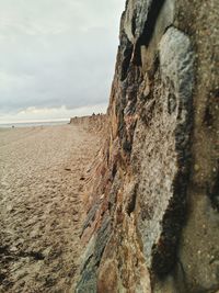 Stone wall at beach against sky