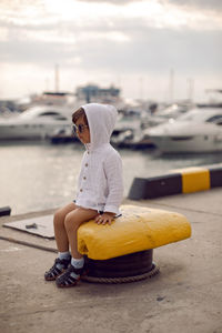 Boy child traveler sitting on the marina with yachts in sochi in the summer